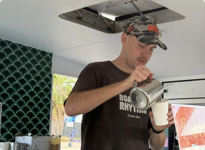 Sam pouring coffee from the Roaming Rhythm caravan